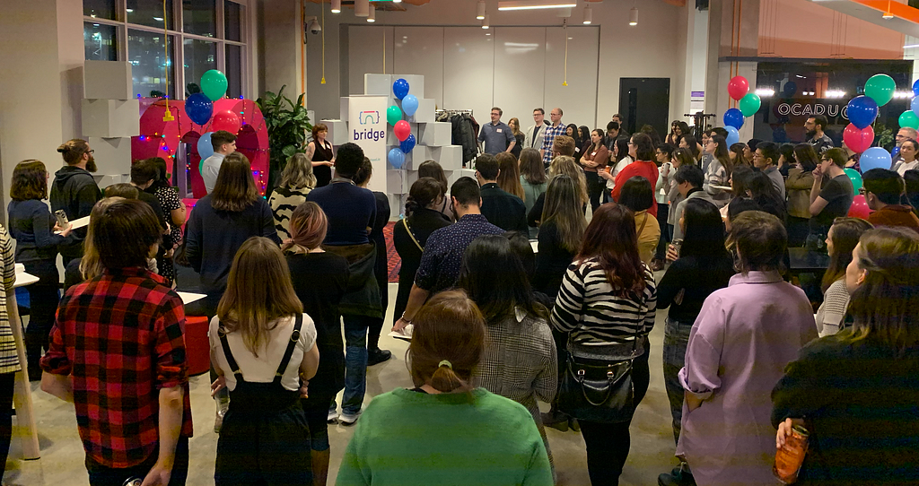 A room filled with many people watching someone speak on a stage.