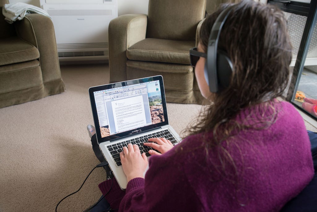 Student who is blind working with laptop on lap inside the living room