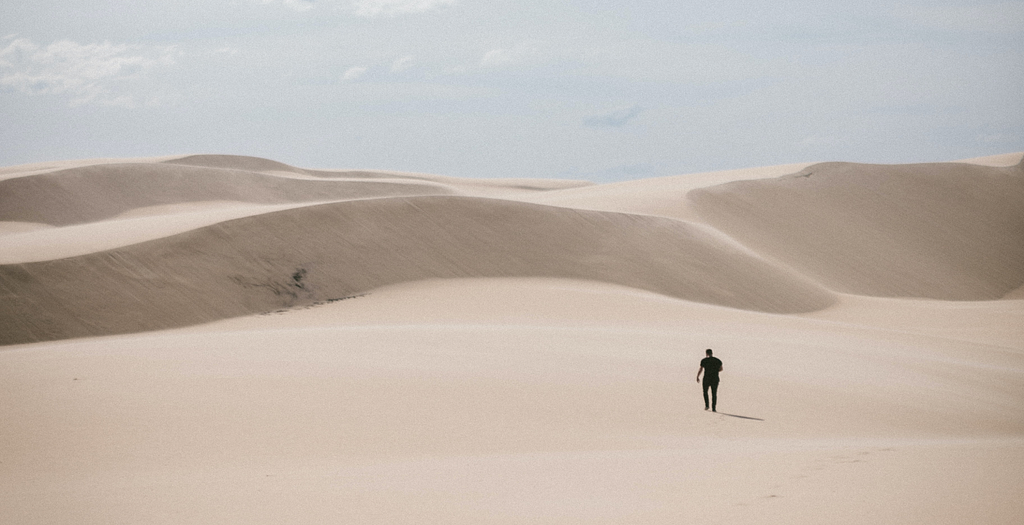 A lone person walking across sand dunes