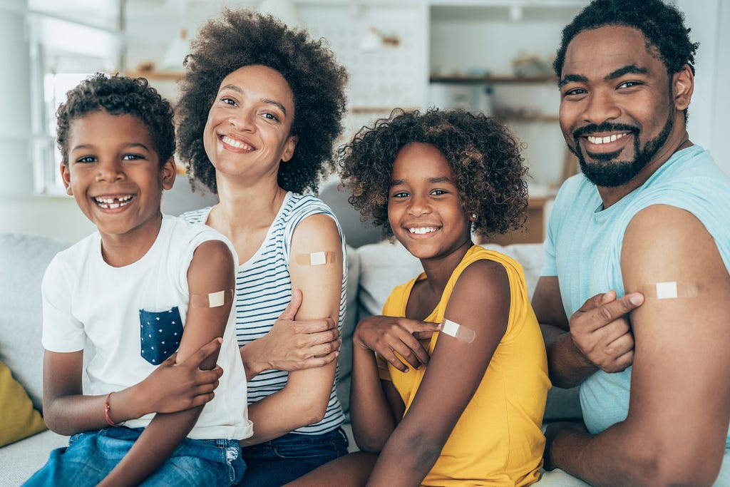 Familia sonriendo ymostrando que se vacunaron