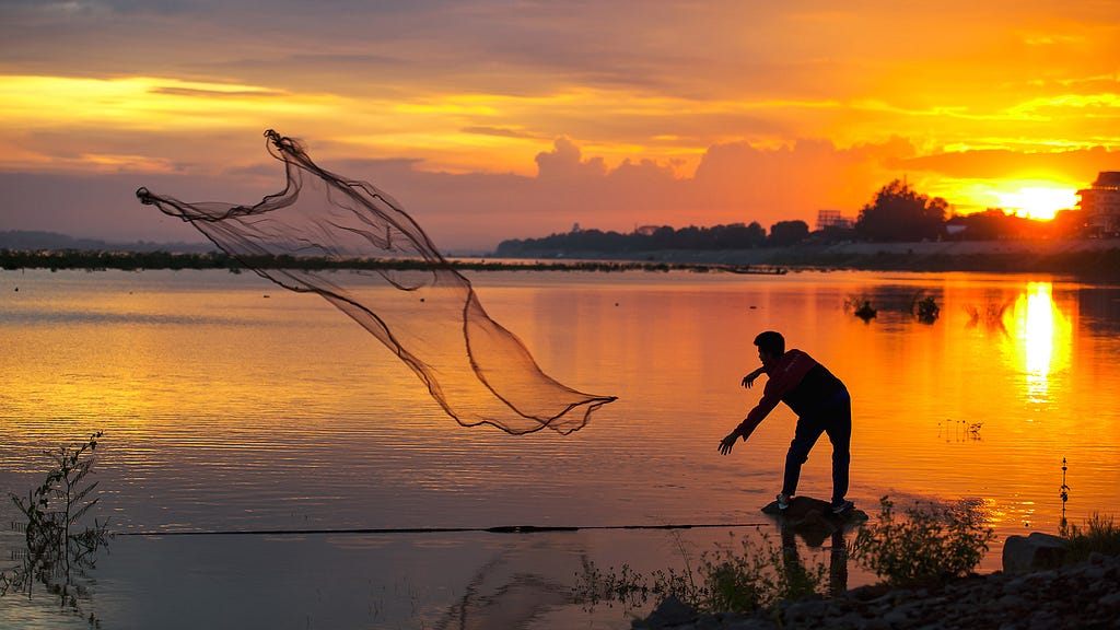 Man throwing his fishing net into the sea.