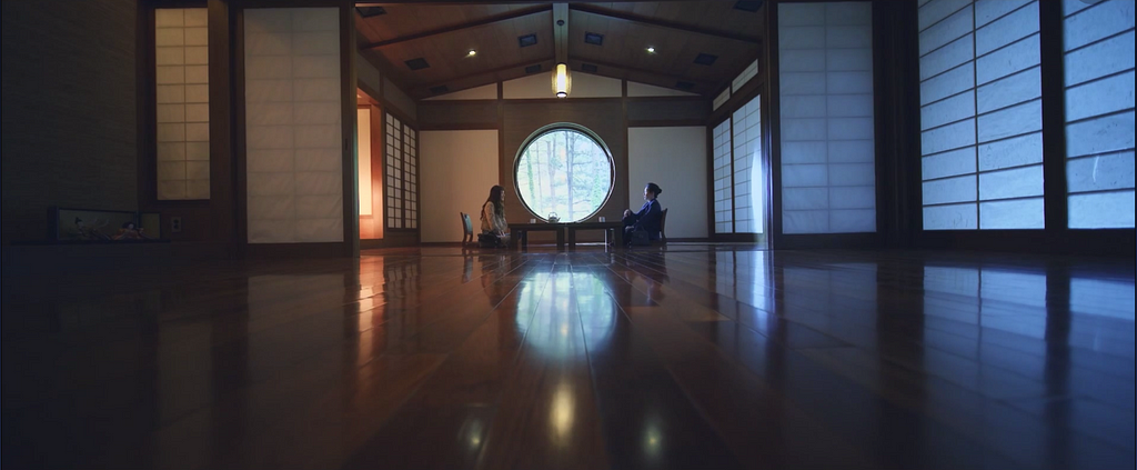 Two people sit on either side of a large round window.