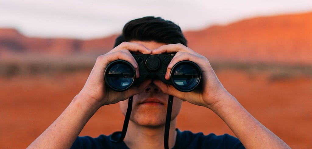 A man using a binoculars looking ahead