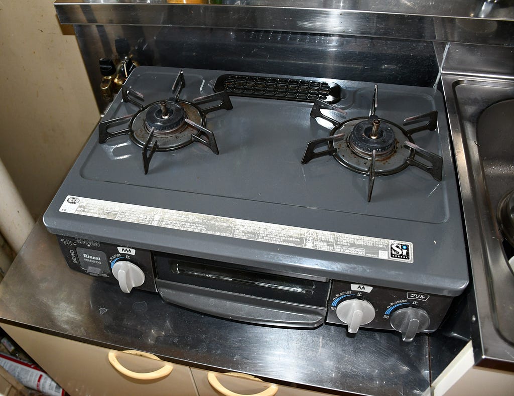 A two-burner gas stove resting on a low kitchen counter in Japan