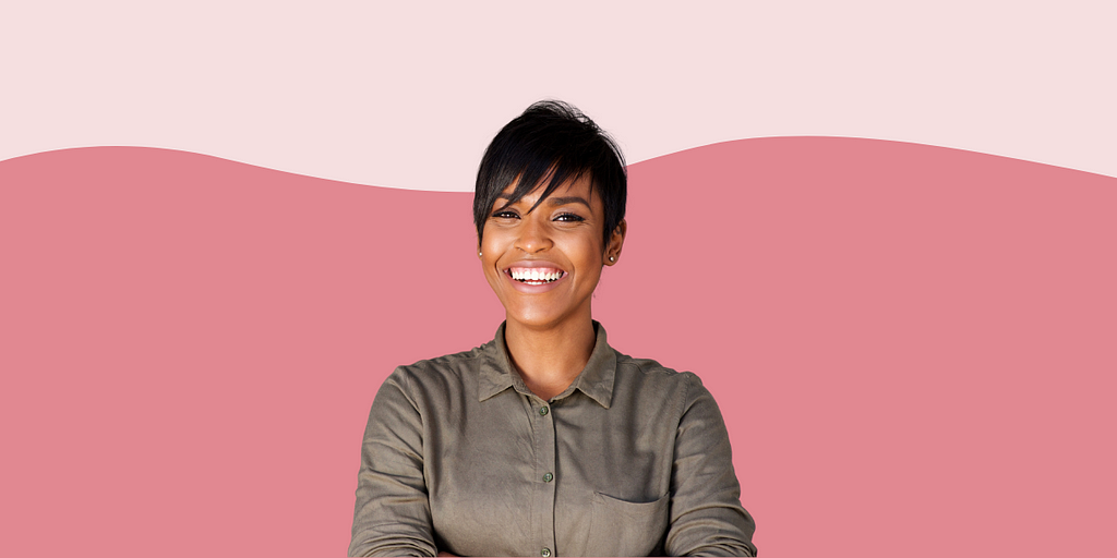 Confident, happy woman smiling against a pink background