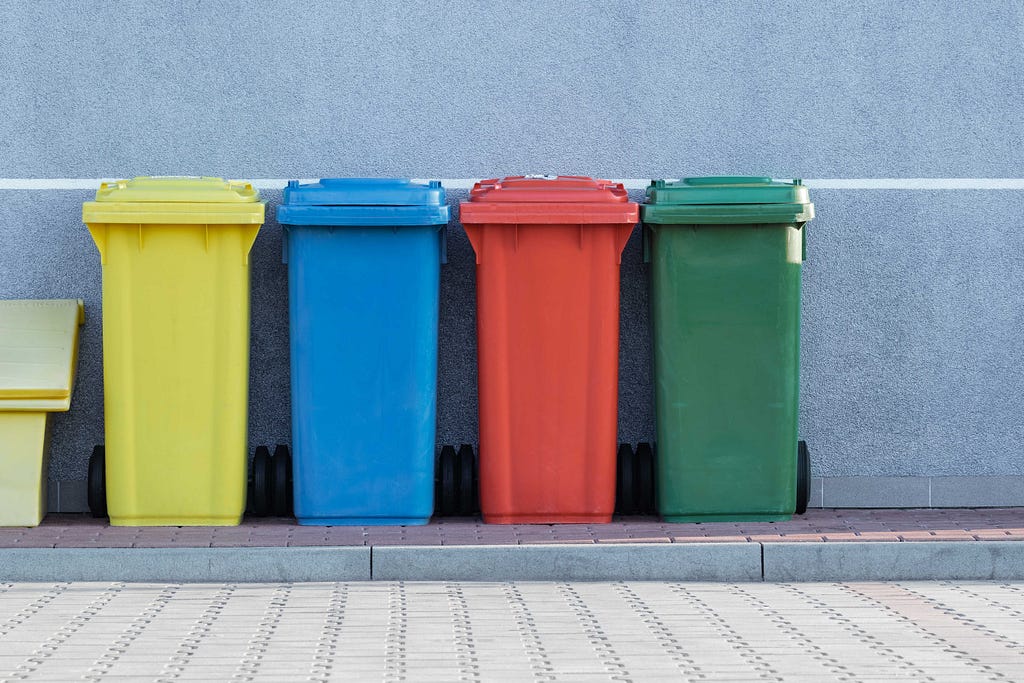 Four garbage bins in a street.