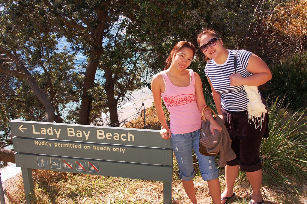 Two women (one may be a girl) stood at sign giving notice of where nudity is permitted