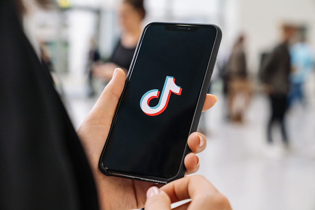 A person holding up a phone with a splash screen with the TikTok logo