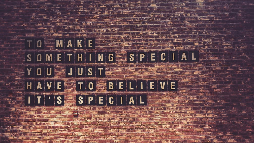 Text on a brick wall reads, “TO MAKE SOMETHING SPECIAL YOU JUST HAVE TO BELIEVE IT’S SPECIAL,” with each word displayed on individual black tiles.
