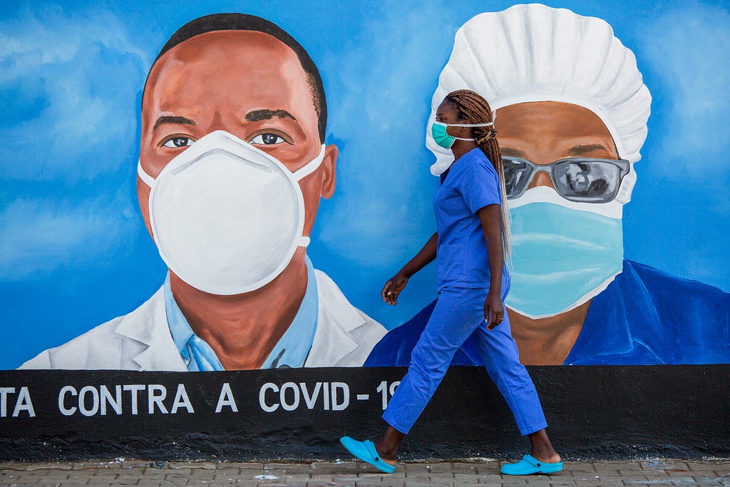 A health care worker walks past a mural at the Polana Caniço hospital in Maputo, Mozambique.