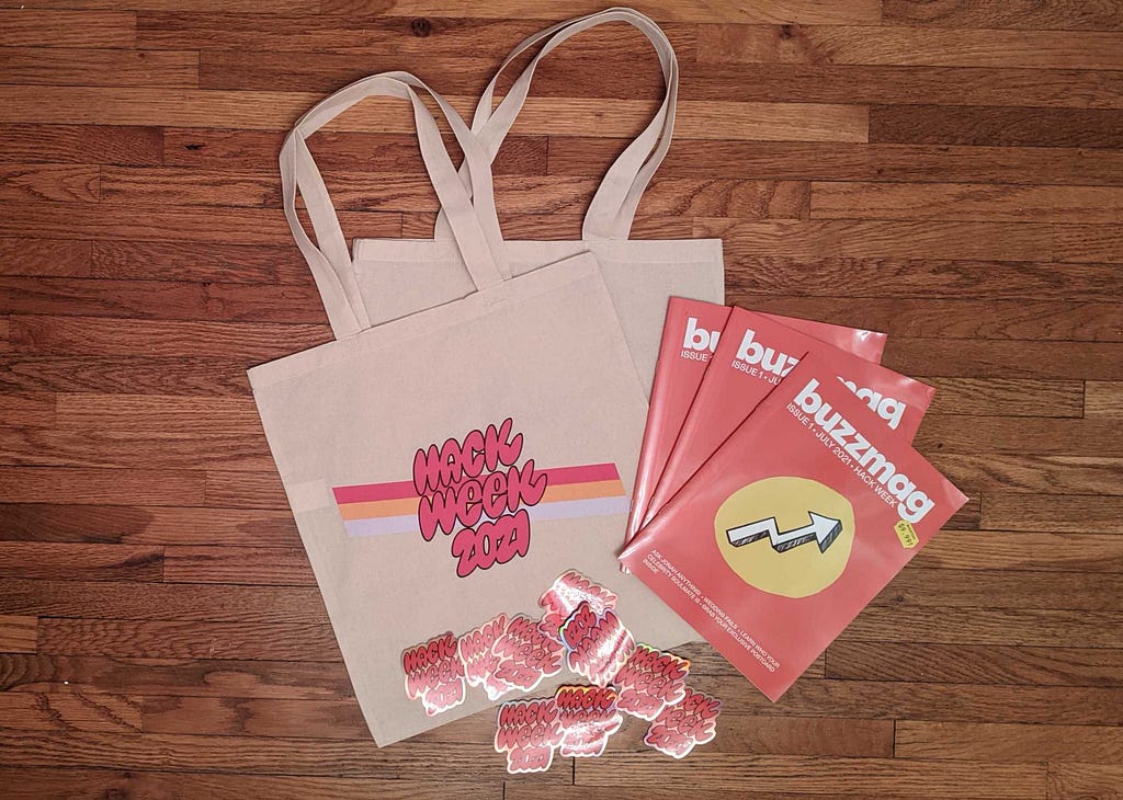 A display of Hack Week 2021 swag which shows the tote bags, printed BuzzFeed Magazine and stickers