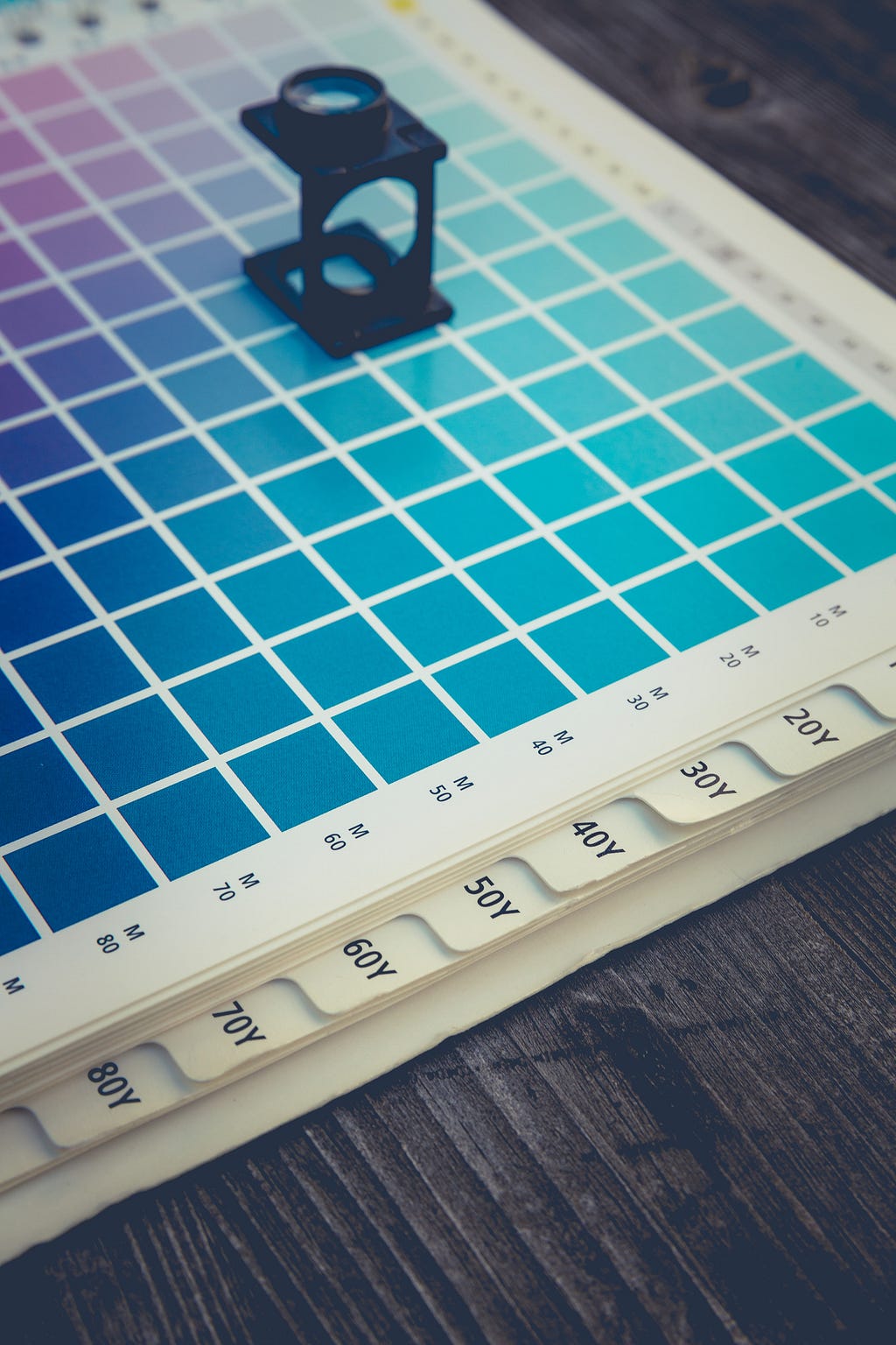 a magnifying lens sitting on top of a catalog of color squares.