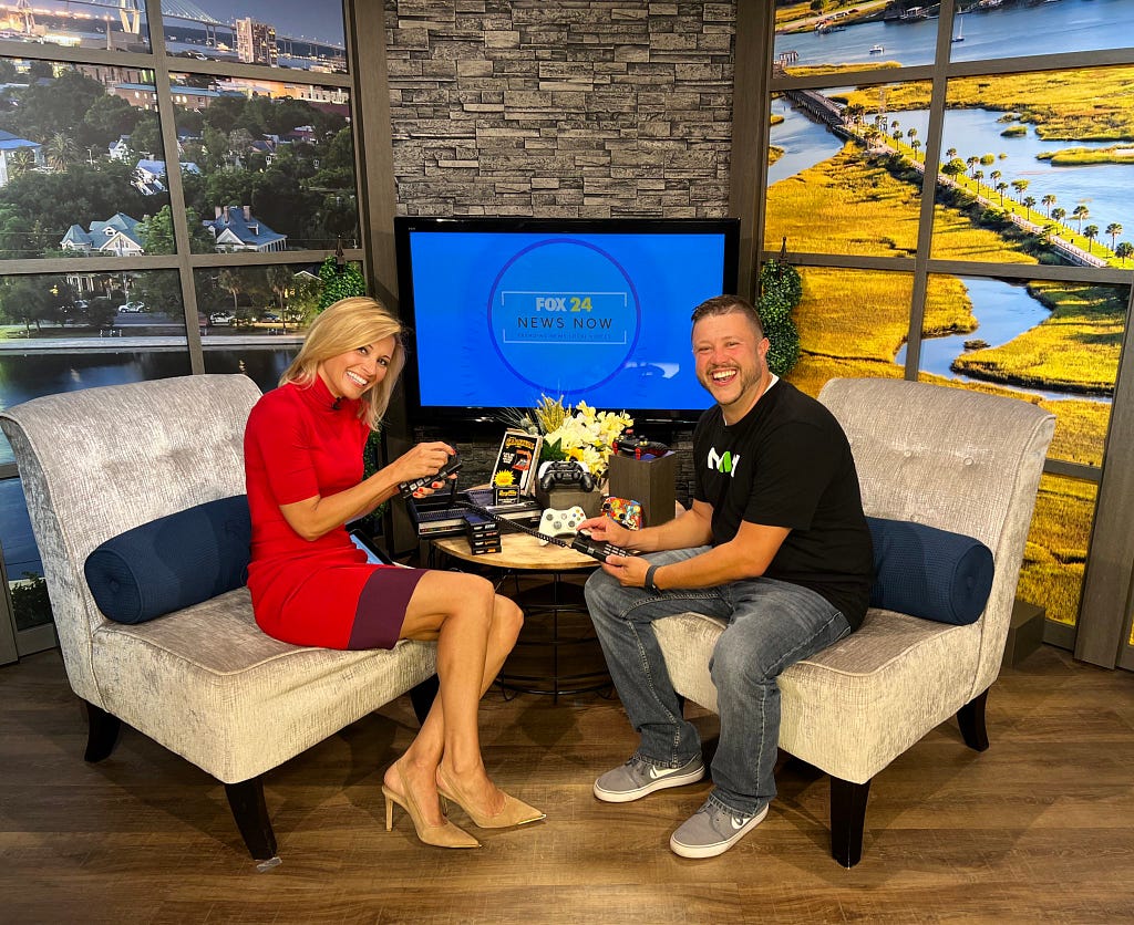 Dex Badgett and Leyla Gulen pictured holding various video game accessories during a Fox 24 News Now Interview