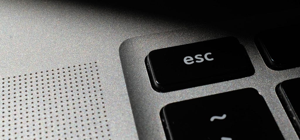 Dim close-up of an escape key on a thin keyboard.