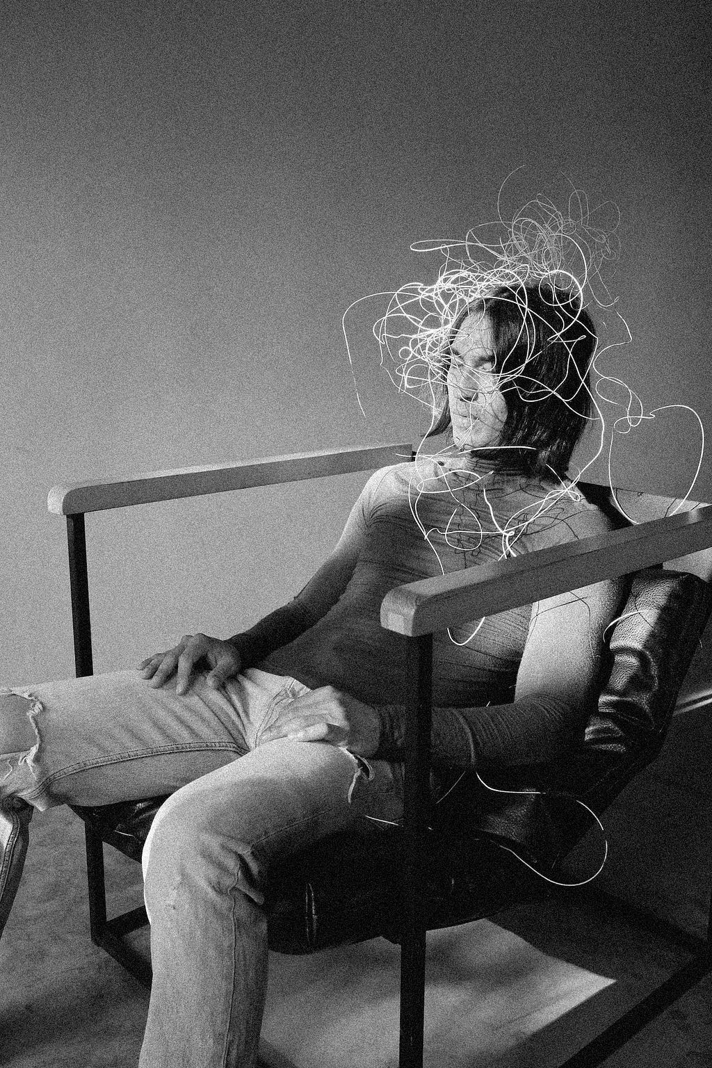 A man in armchair with fictional nodes wrapped around his head