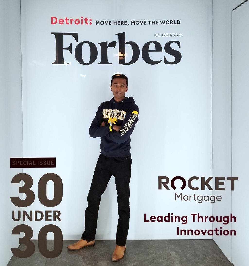 Ismail crosses his arms as he poses in the glass booth that makes it look like he’s on the cover of Forbes Magazine.