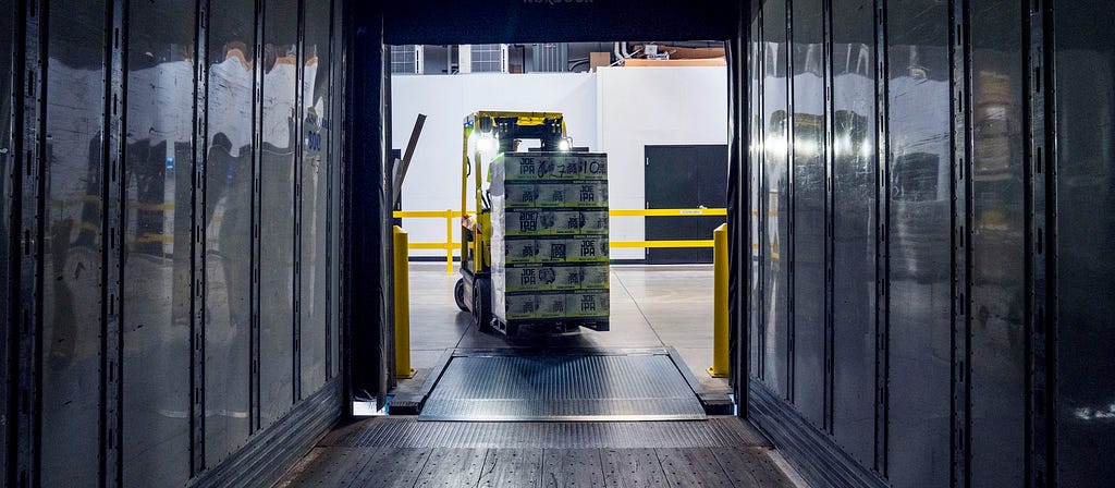 a forklift driving boxes into the back of a truck. Perspective from inside the truck