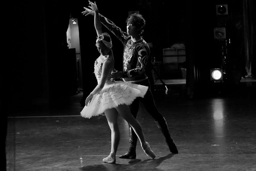 A ballerina and her male partner dance together on stage.