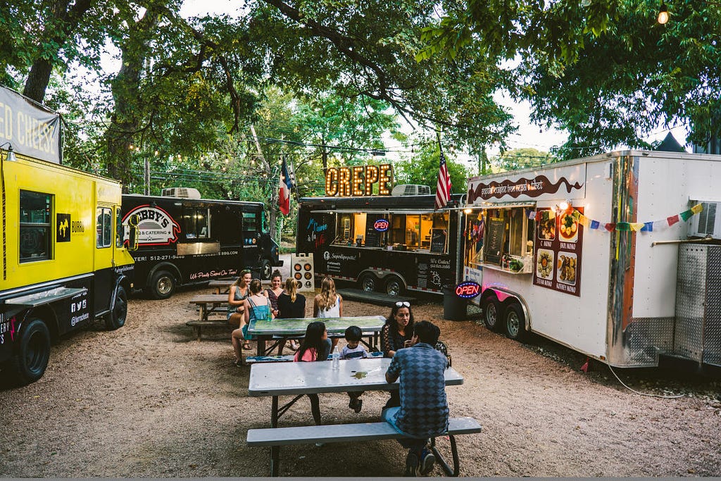 a food court with several food trucks and people sitting and eating there