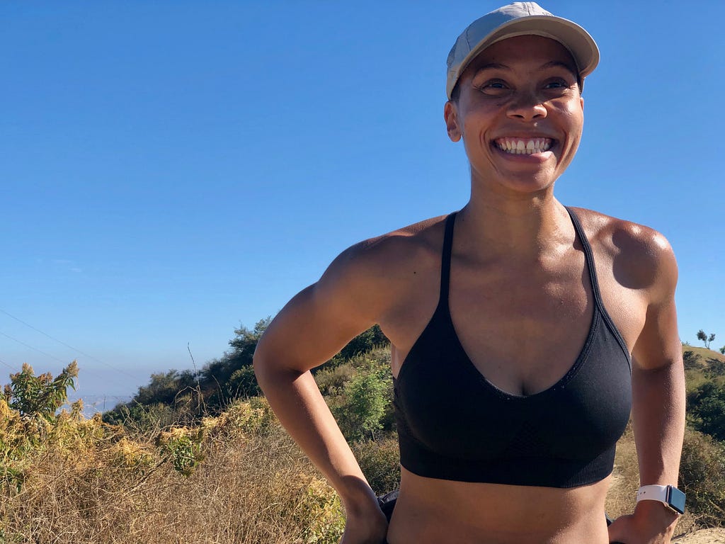 A woman in a sports bra pauses her hike to smile for the camera.