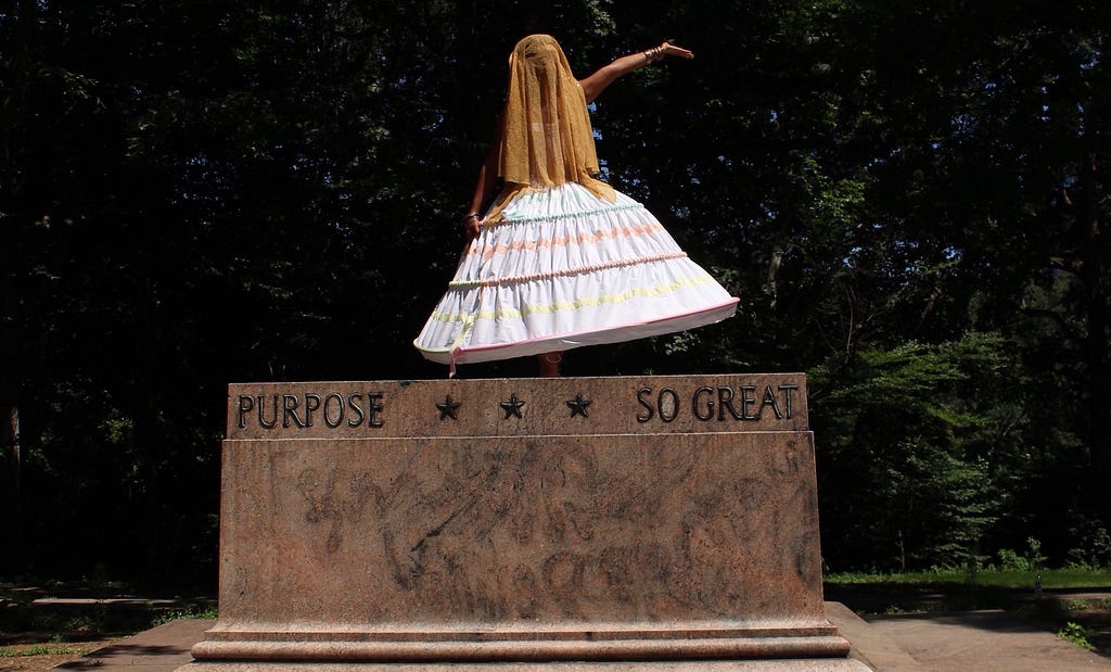 Ada Pinkston, a Black woman, poses on top of a pedestal where a Confederate monument used to stand