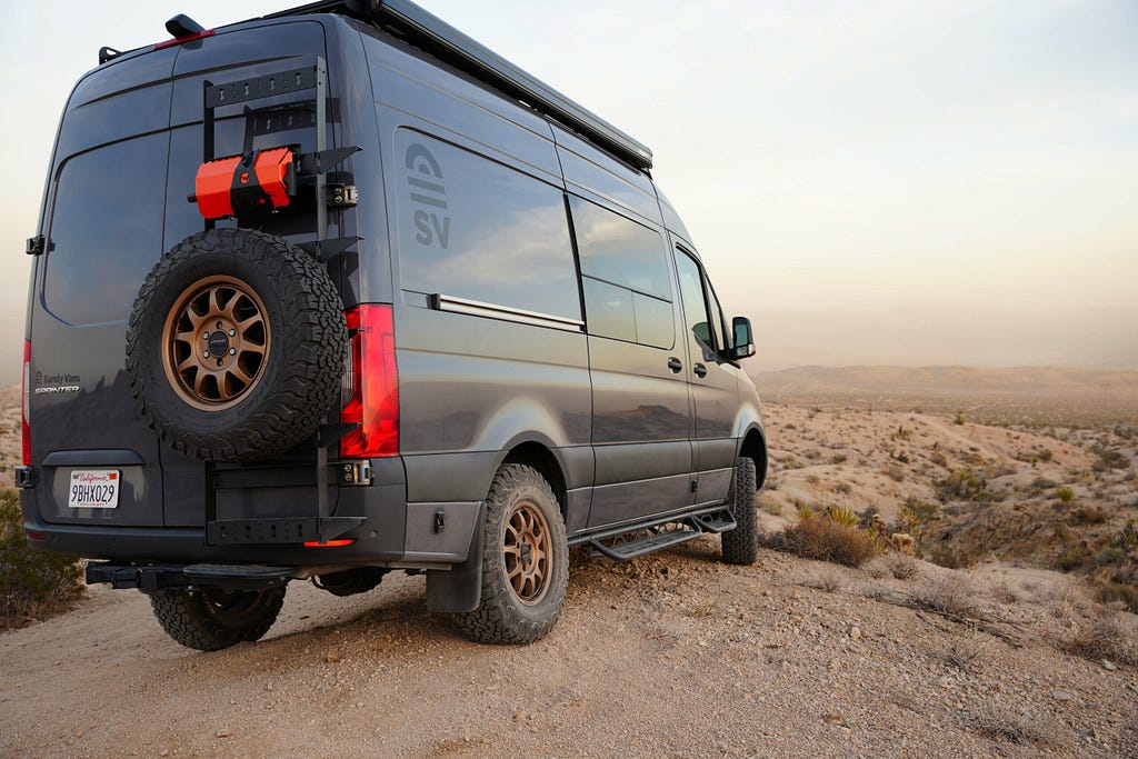 Mercedes Sprinter camper in grey, rear view, overlooking desert