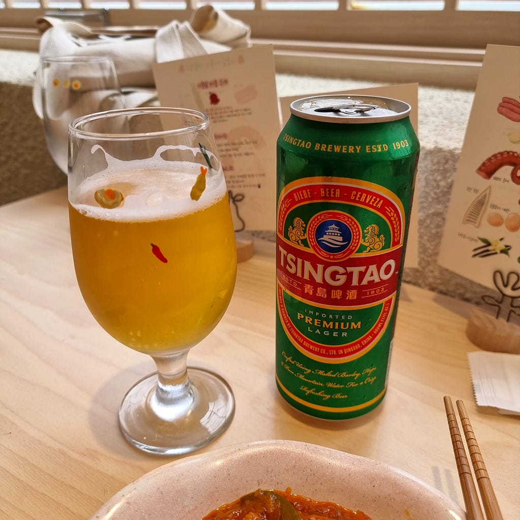 A can and glass of Tsingtao Beer.