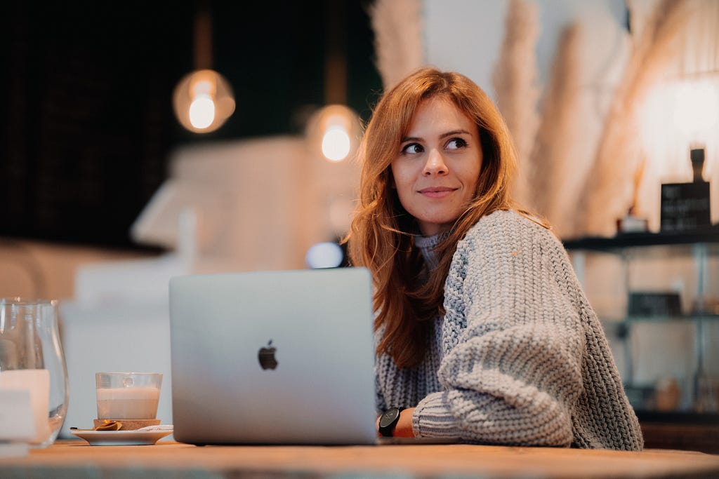 Image taken from unsplash — Image of a woman with a laptop in a cafe