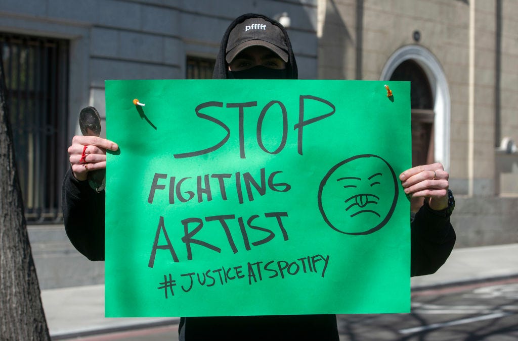 At a worldwide rally by the Union of Musicians and Allied Workers, a musician holds a banner saying “Stop fighting artist” in front of Spotify’s headquarters.