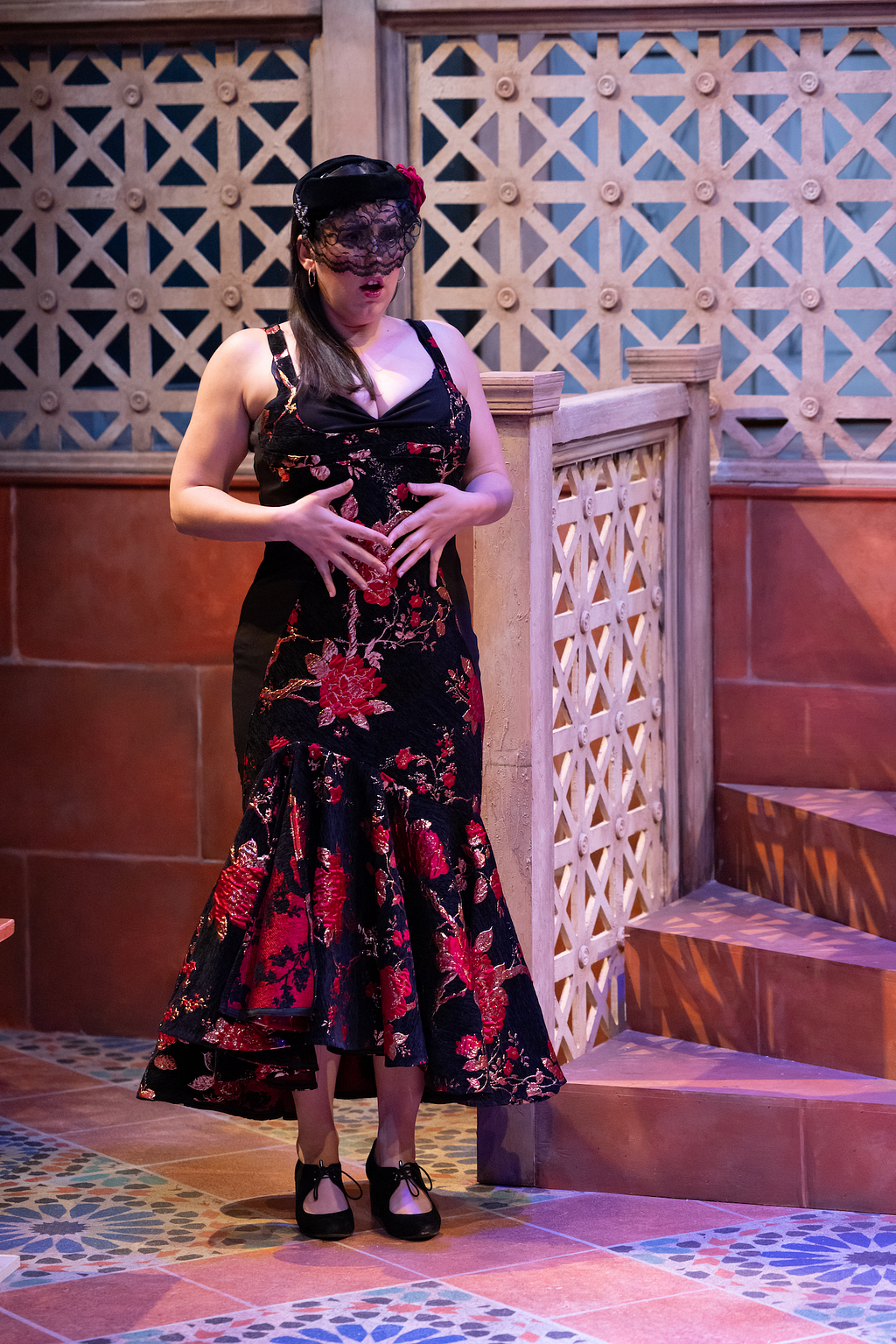 A woman in a black half-veil and a slinky floral dress looks shocked