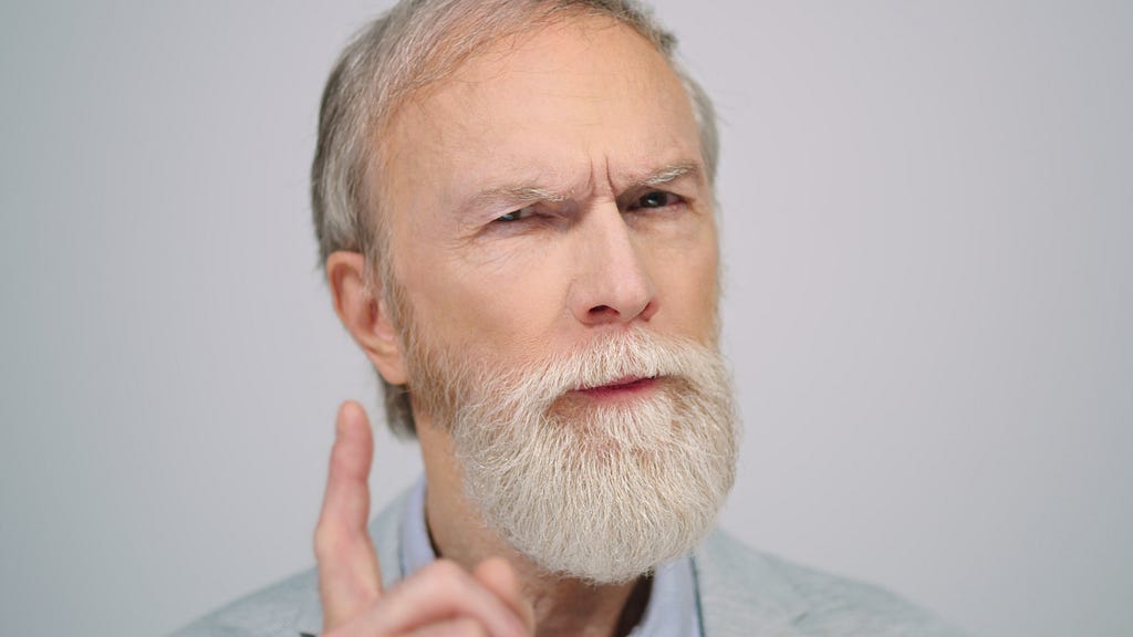 A bearded white man in his sixties looking like a critical person.