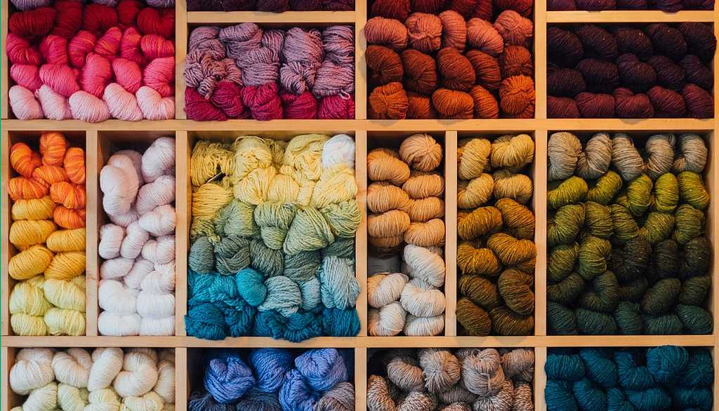 A wall of organized knitting by color, implying indexing.