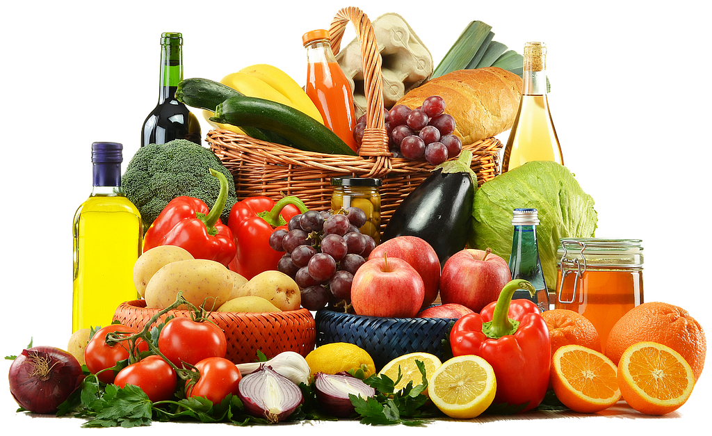 A basket full of colorful fruit and vegetables. There’s also fruit and vegetables outside the basket with bottles of olive.