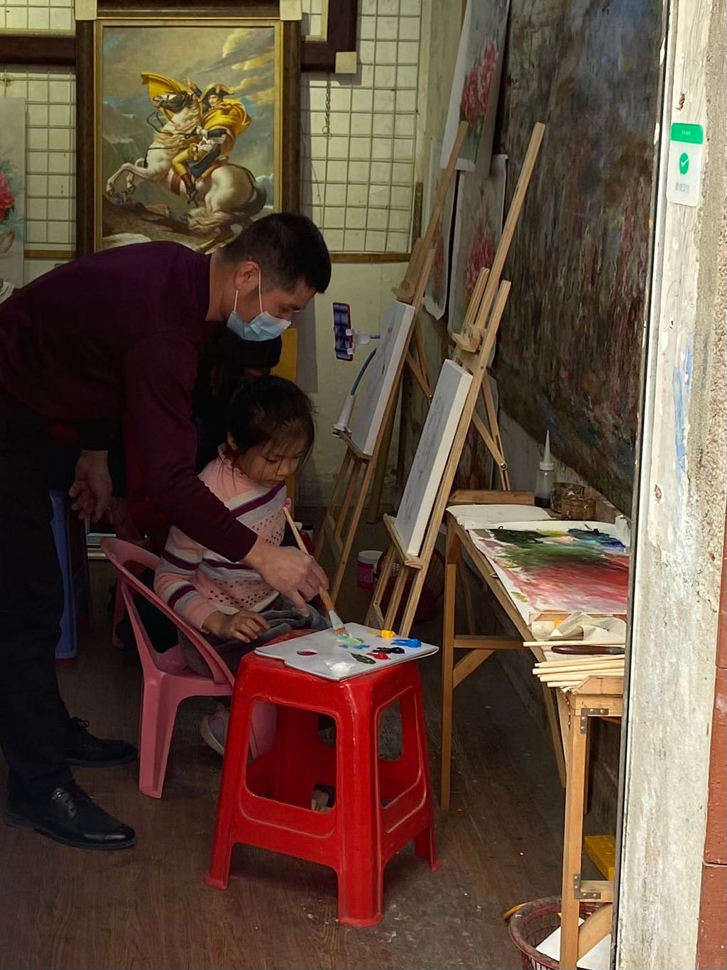 A little girl is learning oil painting from a Dafen Painter