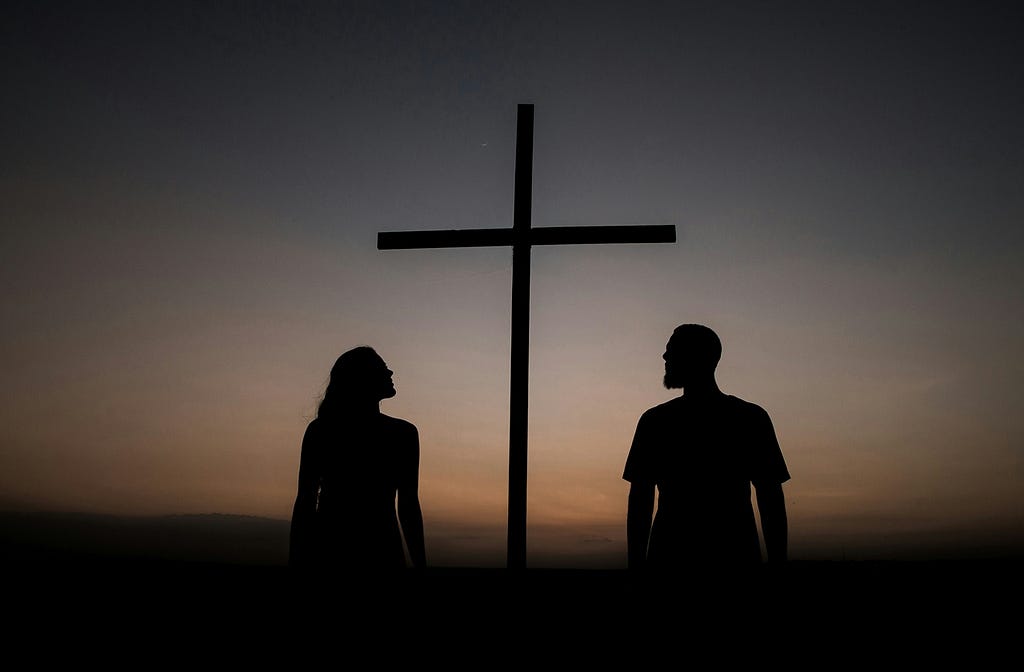 Two people looking at a cross