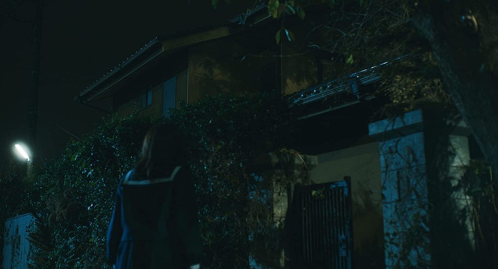 In ‘JU-ON: Origins’ a schoolgirl watches the haunted house, during the night.
