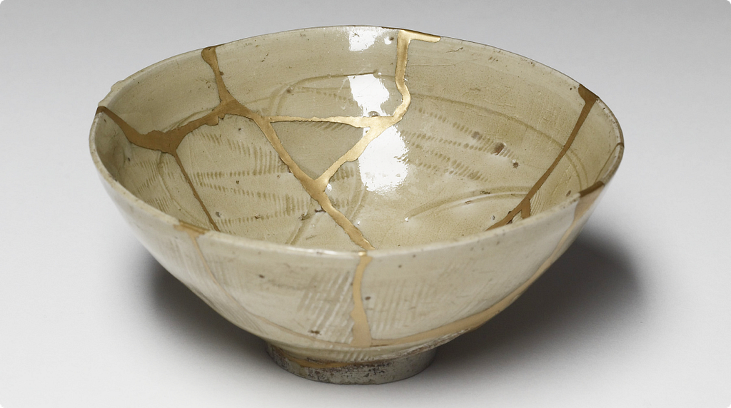 A pale glazed Chinese stoneware bowl, its breaks rejoined with branching seams of gold-brown lacquer.