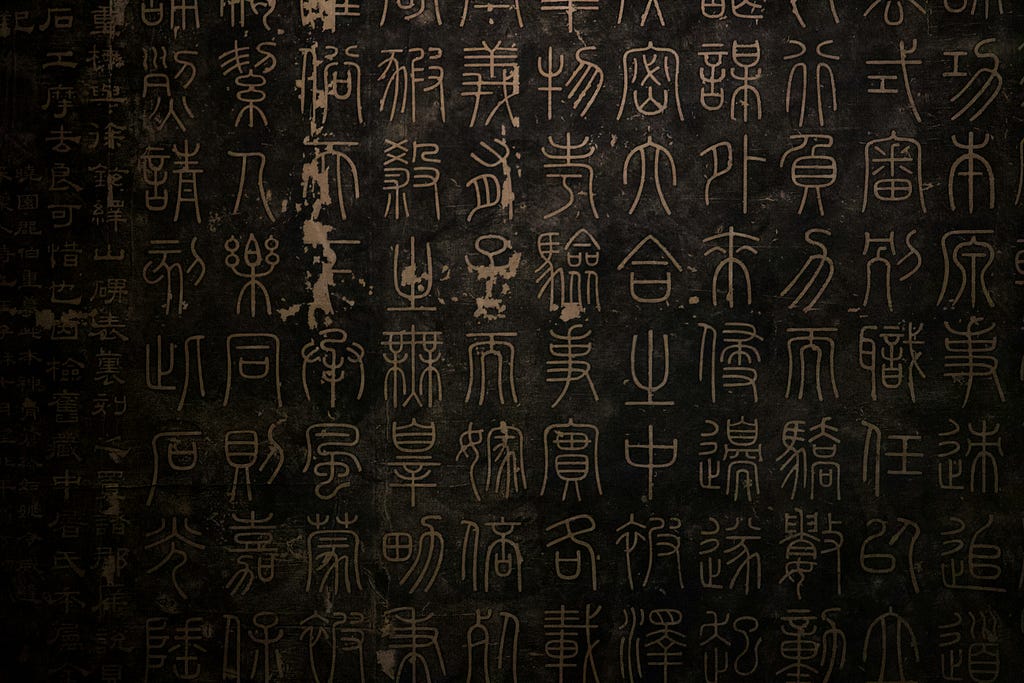 An image shows language like inscriptions on black stone.