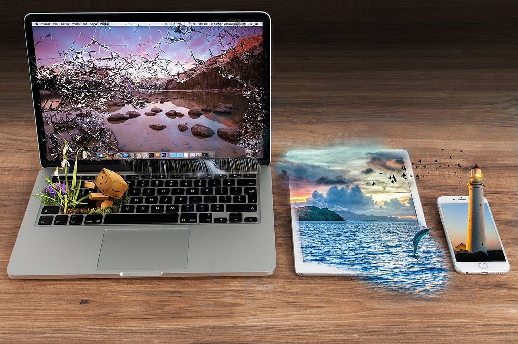 Um notebook, um tablet e um celular posicionados sobre uma mesa de madeira mostram imagens que ultrapassam suas telas, simulando a Realidade Aumentada em diferentes dispositivos. | Foto encontrada em: Pixabay.com