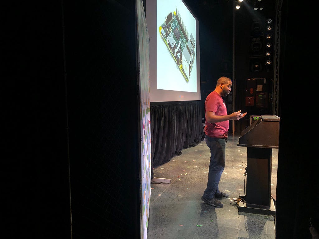 Marc Aupont standing on stage at a podium giving a talk at a tech conference.