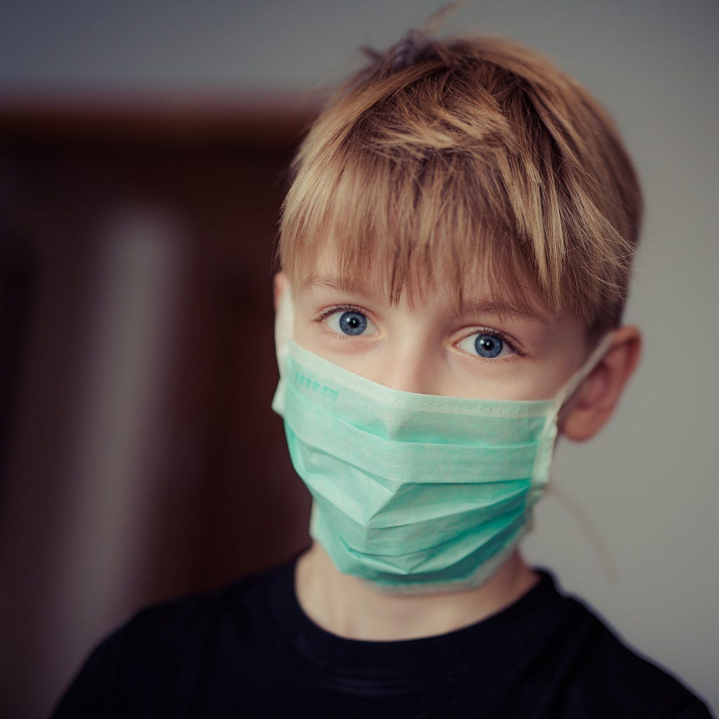 Boy wearing medical mask in interior of building