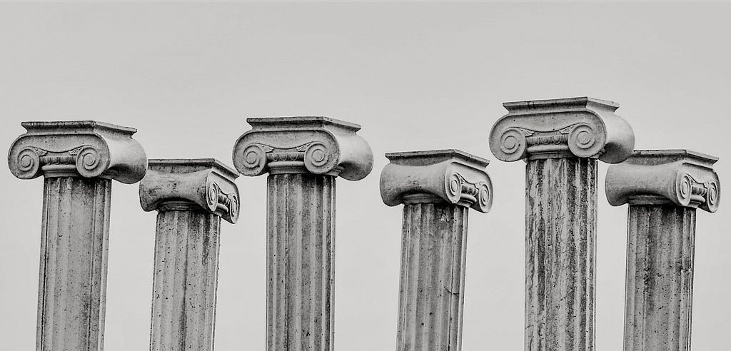 The top halves of 6 ancient pillars in greyscale.