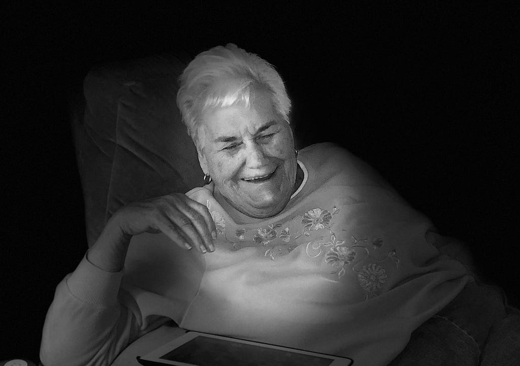 My mother smiling as she plays on her iPad.