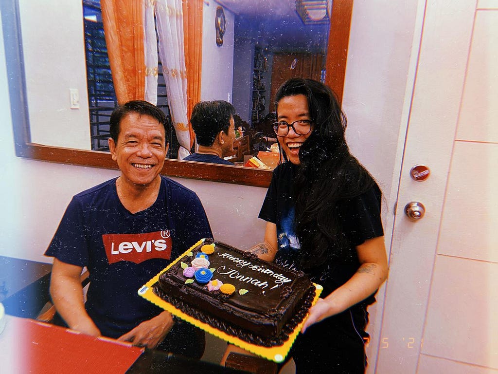 My father and I on my 28th birthday in 2022. We’re both smiling. I’m holding a chocolate cake with “Happy Birthday, Jonnah” written on it.