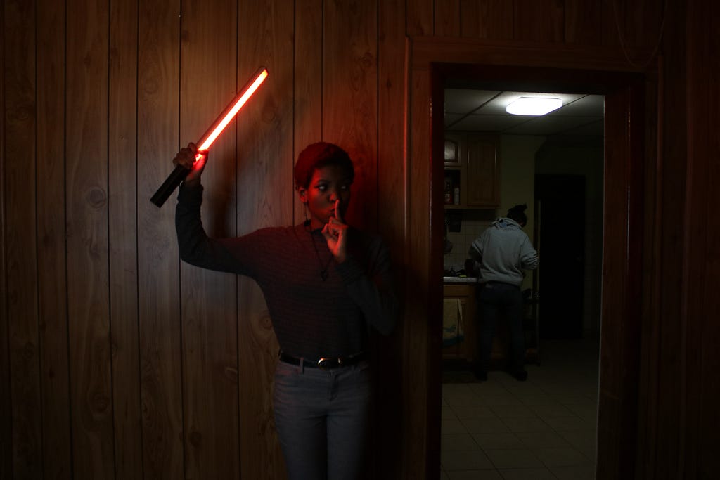 A woman sneaking up behind another person with a light stick