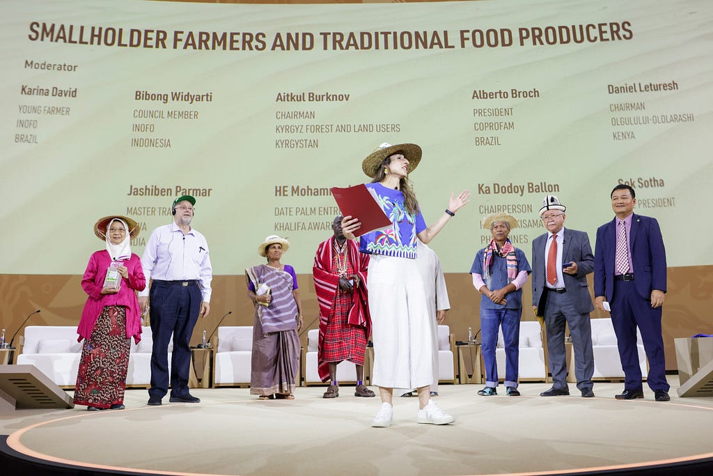 People on stage in front of a background sign that reads “smallholder farmers and traditional food producers”.