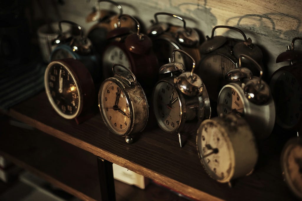 Vintage alarm clocks on a wooden table inside an old building.