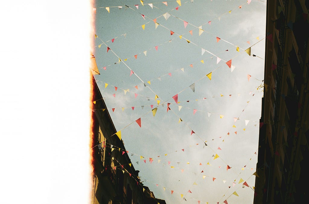 A picture with many triangular flags against the sky