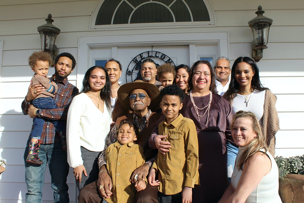 Mixed family with adults and kids standing in front of a home.