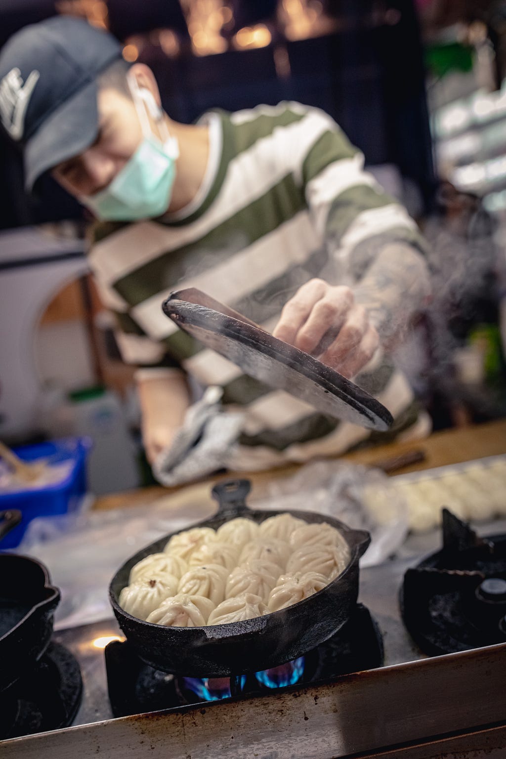 street vendor cooking pork buns in cast iron pans with wooden lid in Taiwan